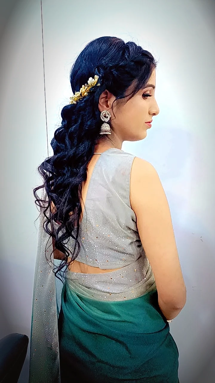 Side Dutch crown braid pinned with a gold floral brooch over long textured curls